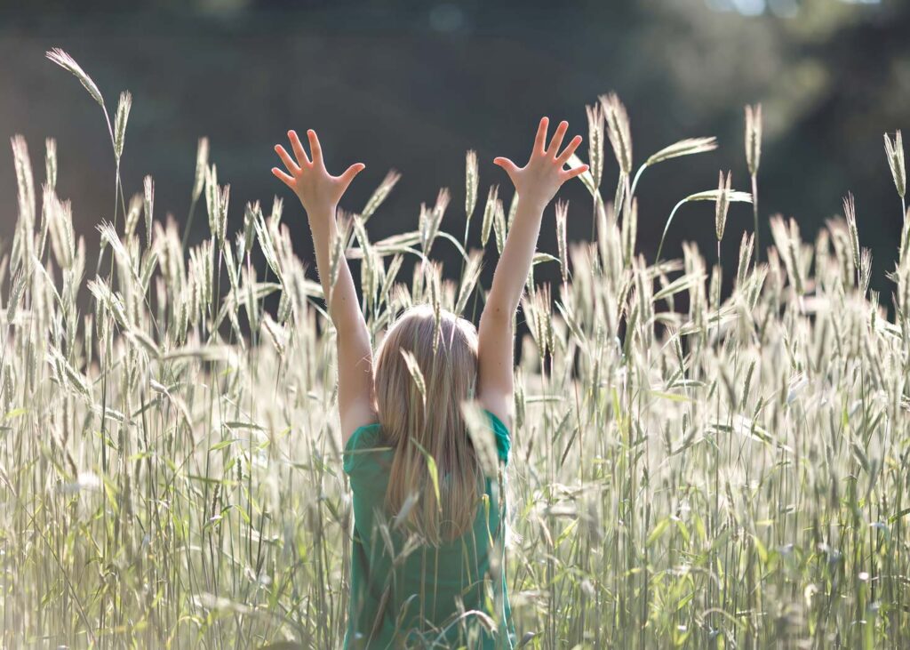 Girl standing in a field with her arms up